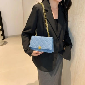 Blue denim crossbody bag with gold chain strap and quilted design shown on model