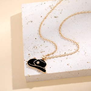 Detailed close-up of a gold necklace with a black enamel cowboy hat pendant and star detail