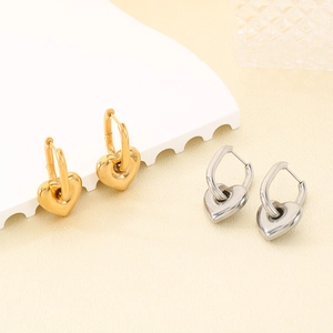 Boucles d'oreilles cœur polies en or 18 carats et argent sur un support blanc texturé