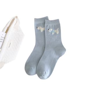 Calze in cotone azzurro con graziosi motivi a cane bianco e fiocchi su sfondo bianco