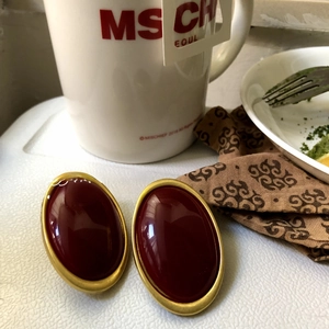 Detail view of retro oval deep red stud earrings with elegant gold metal trim