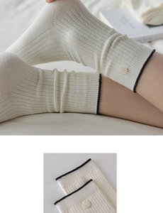 Detailed view of cream-colored ribbed socks with black trim and elegant pearl button