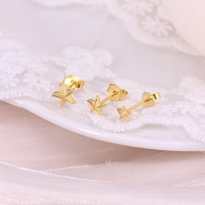 Detailed macro view of three gold-plated starfish stud earrings with fine textures