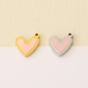 Macro detail of pink enamel heart pendants with gold and silver beaded metal edges