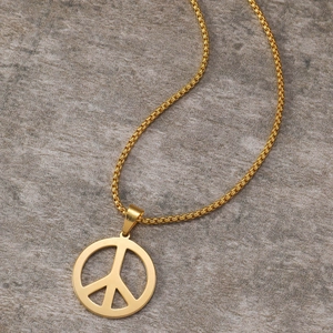 Close-up of golden peace sign pendant with box chain on grey stone texture background
