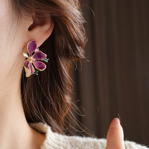 Detail von Vintage-Blumenohrring mit lila Emaille und Kristallen am Modell