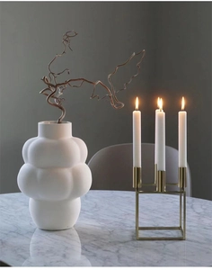 Detailed macro shot of white bubble ceramic vase and golden metal candle holder decoration