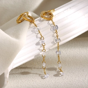 Close-up of gold-plated long tassel earrings with clear cubic zirconia on soft white fabric