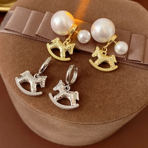 Detail of gold and silver horse-shaped earrings with pearls on brown velvet jewelry box