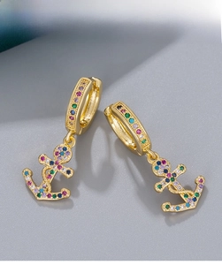 Detail view of gold anchor earrings with colorful micro-set rhinestones on grey background