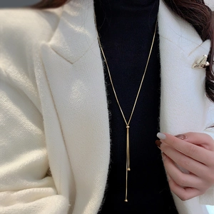 Close-up of adjustable 18k gold snake chain necklace on a model wearing black turtleneck