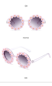 Front and side views of light pink daisy sunglasses for girls with transparent temples