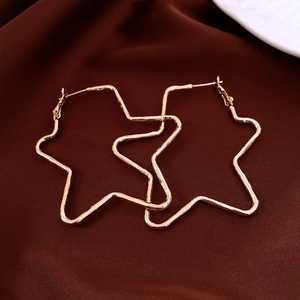 Close-up of minimalist rose gold star-shaped hoop earrings on dark satin fabric