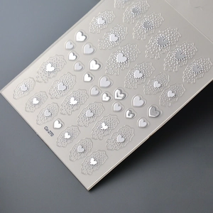 Detailed macro view of 5D embossed heart nail art stickers with silver and white relief textures