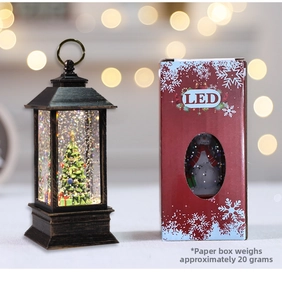 Macro view of vintage bronze LED Christmas lantern with miniature tree and packaging