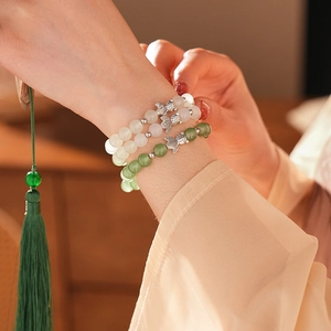 Detail of beaded chalcedony bracelet with fish charms on a woman's wrist