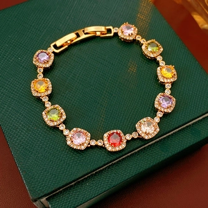 Close-up of vintage gold bracelet with colorful square zircons on green leather