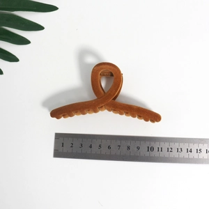 Brown velvet claw clip 12cm hair accessories for women shown with green leaves