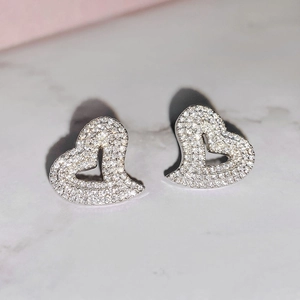 Macro shot of silver heart studs with pavé cubic zirconia on marble background