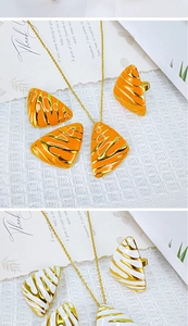 Detailed macro of enamel jewelry sets with orange and white wave patterns on gold metal