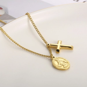 Detail showing gold oval Virgin Mary coin and minimalist cross pendant on a fine chain
