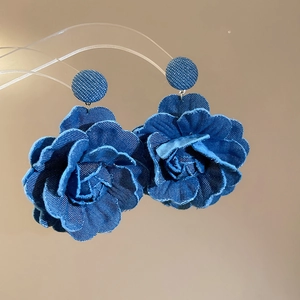 Detail of blue denim fabric rose earrings with layered petals and textile studs