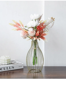 Close-up of golden iron lantern vase with a glass insert and white faux peonies
