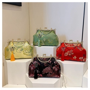 Detail view of four silk embroidered shell bags with pearl handles and silk tassels