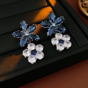Macro detail of silver floral earrings with navy and white crystals on jewelry tray