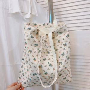 Detail of floral pattern cotton tote bag with blue and orange flowers on ivory canvas