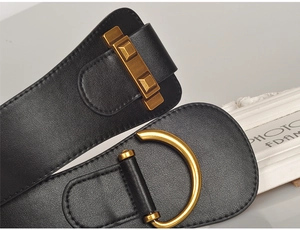 Macro detail of wide black leather belt with antique gold D-ring buckle and rivet accents