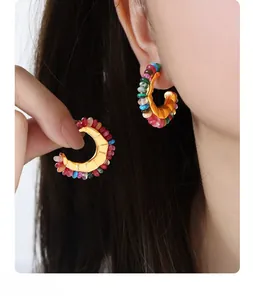 Detail of C-shaped gold vintage hoop earrings with colorful beads on a model