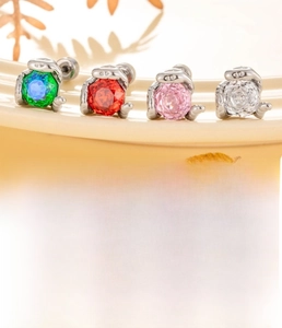 Macro view of four colorful zircon snake earrings on a ceramic tray with titanium posts