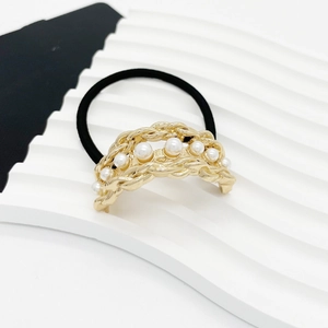 Detail of elegant gold alloy chain hair tie with white pearls on a wave texture stand