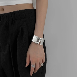Vue détaillée d'un bracelet ouvert métallique irrégulier avec une finition miroir argentée