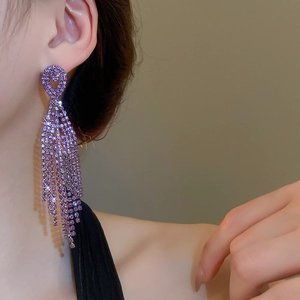 Detailed close-up of long purple tassel earrings with sparkling rhinestones on a model