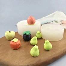 Detail of white silicone mold with fruit-shaped crafts like pear and peach on wood