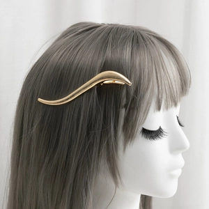 Golden wave hair clip with matte metal texture on grey hair, minimalist S-shape accessory