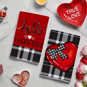Two red Valentine's Day kitchen towels with buffalo plaid on white marble surface