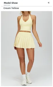 Detail of creamy yellow halter top and pleated skirt yoga set on model in studio