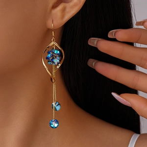 Detailed close-up of long tassel earrings with blue crystals and twisted gold frames