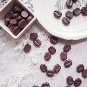 Flat lay of resin coffee bean charms for DIY phone case making on a white lace background