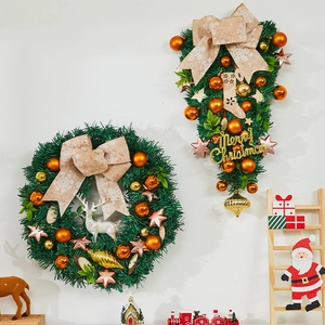 Detailed view of Christmas wreath and teardrop swag with reindeer decor on white wall
