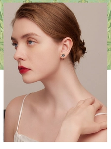 Close-up of a model wearing minimalist black cat-shaped 925 silver stud earrings