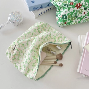 Detail view of green floral makeup bag storage capacity with zipper and interior brushes