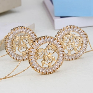 Détail de pendentifs ronds plaqués or avec pierres zircons et motifs d'enfants