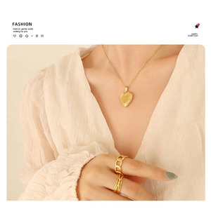 Detail of 18K gold plated heart locket necklace and matching rings on a model
