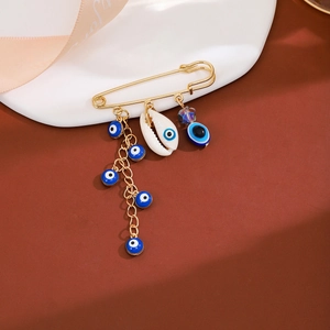 Detailed view of evil eye charms and shell beads on a golden tassel safety pin brooch