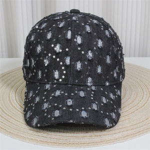 Detail view of black denim baseball cap featuring vintage distressed holes and silver sequins