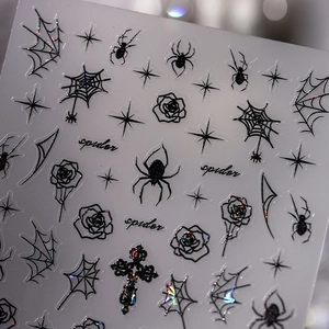 Primer plano de pegatinas de uñas góticas con telarañas, rosas y cruces en negro